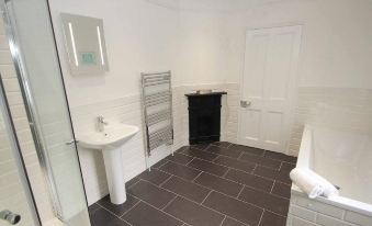 a modern bathroom with white walls , gray floor tiles , and a sink , shower , and toilet at Panacea
