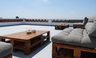 a rooftop patio with several wooden tables and chairs , some of which are covered in cushions at MirArte