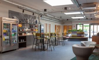 a modern restaurant with a bar and dining area , featuring multiple chairs and tables as well as potted plants at Best Western Plus Hotel Amstelveen