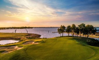 a beautiful golf course with a lake in the background , surrounded by lush green grass at The Sebel Yarrawonga Silverwoods