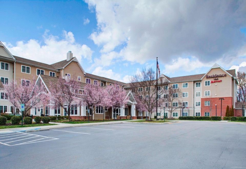 a large , multi - story building with a parking lot in front of it and cherry blossom trees nearby at Residence Inn Richmond Chester