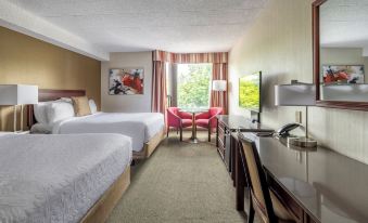 a hotel room with two beds , a desk , and a window , decorated in white and brown colors at Hotel WelcomInns