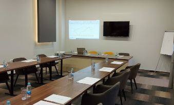 a conference room with a long table and chairs , water bottles , and a television mounted on the wall at Hotel River