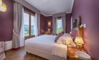 a luxurious bedroom with a large bed , white sheets , and purple walls , overlooking a beautiful view at Albergo Posta Marcucci