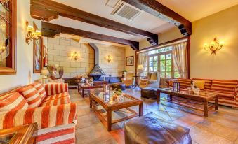 a cozy living room with wooden beams on the ceiling , a fireplace , and various pieces of furniture at Hotel Spa Villalba