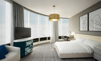 a hotel room with a large bed , a flat - screen tv , and a window overlooking the city at The MC Hotel, Autograph Collection