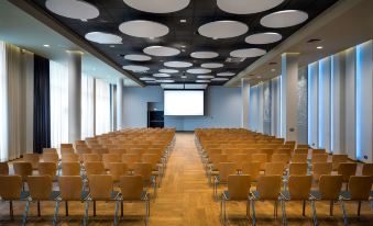 a large conference room with rows of wooden chairs arranged in a semicircle , and a projector mounted on the wall at Park Inn by Radisson Katowice