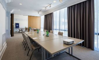 a conference room with a long table , chairs , and green bottles set up for a meeting at NH Luxembourg