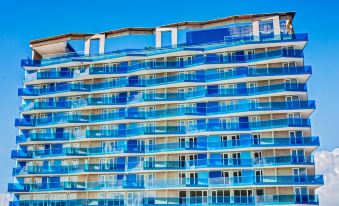 a large , modern building with a unique blue and white facade , situated on a beach at Cosmos Pacifico Hotel