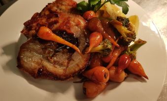 a plate of food on a dining table , consisting of a piece of meat , vegetables , and sauce at The Fairy Falls Hotel