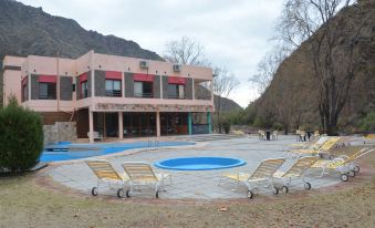 a large outdoor pool surrounded by lounge chairs , with a building in the background and people relaxing on benches at Cabanas Del Sol