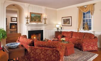 a cozy living room with red couches , a fireplace , and a painting on the wall at The Inn & Tavern at Meander