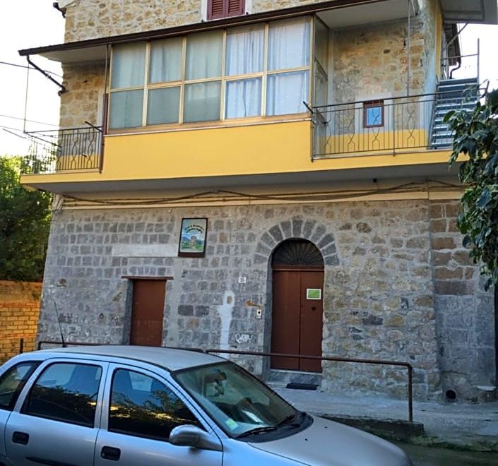 a brick house with a car parked in front and a yellow railing on the side at Le Quattro Stagioni