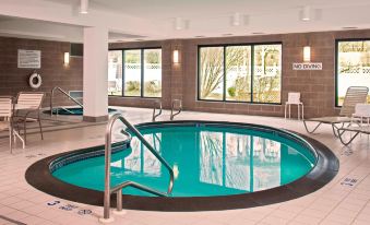 an indoor swimming pool with a hot tub , surrounded by windows that let in natural light at Courtyard Newburgh Stewart Airport