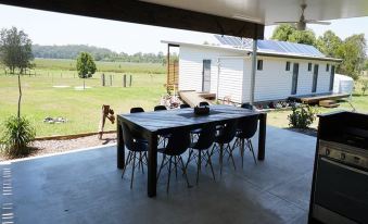 a large wooden table and chairs are set up on a patio overlooking a field at Narangba Motel (Formerly Brisbane North B&B and Winery)