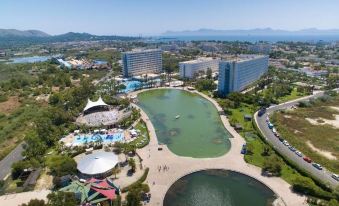 a bird 's eye view of a resort with a large body of water surrounded by buildings and people at Club Mac Alcudia