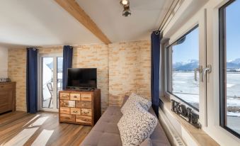 a cozy living room with a couch , a television , and a window overlooking a snow - covered landscape at Hotel Haus am See