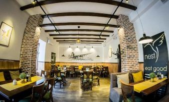 a restaurant with brick walls , wooden floors , and chairs around tables under a sloping ceiling at Nest