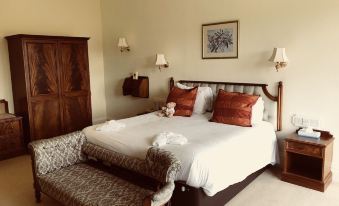 a large bed with a wooden headboard and footboard , white linens , and two orange pillows at Dryburgh Abbey Hotel