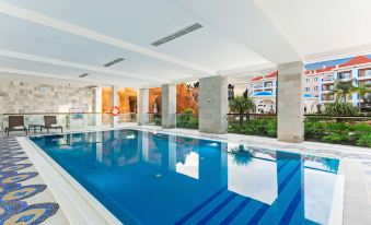 an indoor swimming pool with a clear blue water , surrounded by white walls and a wooden ceiling at Hilton Vilamoura As Cascatas Golf Resort & Spa