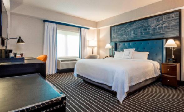a large bed with white sheets and a blue headboard is in the center of a room at Courtyard Boston Brookline