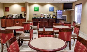 a dining area with several tables and chairs , a counter , and a tv mounted on the wall at Comfort Suites Gadsden Attalla