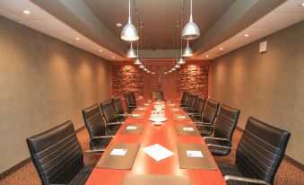 a long wooden conference table with black chairs , papers , and paper splitters in a dimly lit room at Best Western Parkway Inn  Conference Centre