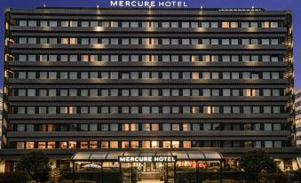 a large hotel with a large sign above the entrance and a covered walkway in front of it at Mercure Milano Agrate Brianza