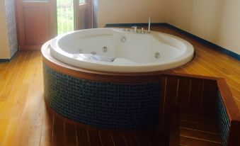 a white bathtub with blue mosaic tiles , situated in a bathroom with wooden flooring and large windows at Moo