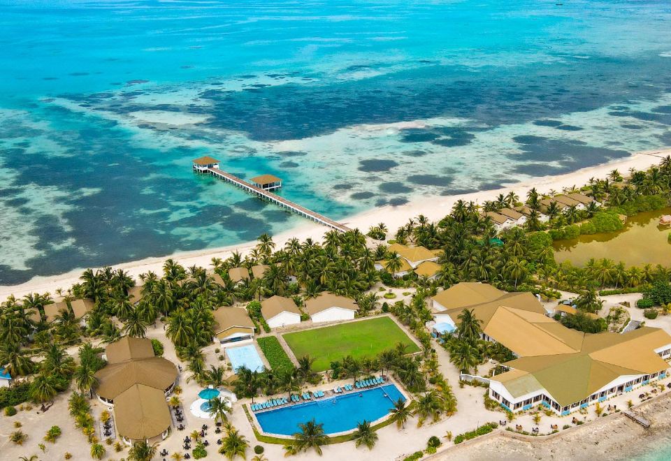 a bird 's eye view of a resort with a pool , palm trees , and an ocean at South Palm Resort Maldives