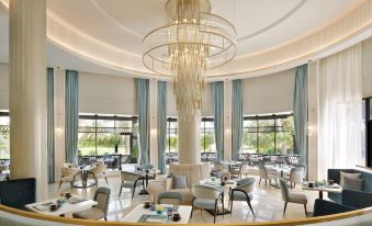 a large , modern dining room with multiple tables and chairs arranged for a group of people at Movenpick Hotel Bahrain