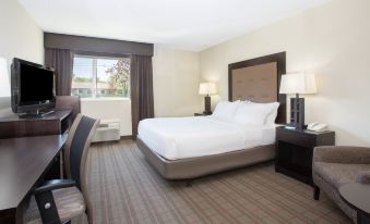 a large bed with white linens is in a room with two lamps and a window at Holiday Inn Riverton-Convention Center