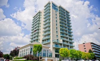 a modern , white - colored apartment building with balconies and a green lawn , under a blue sky dotted with clouds at The Waterside Inn