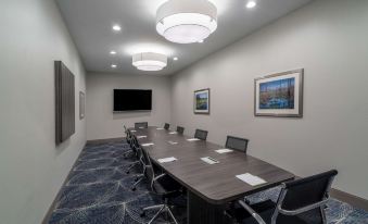 a conference room with a long table , chairs , and a television mounted on the wall at La Quinta Inn & Suites by Wyndham Tifton