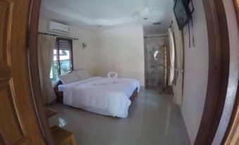 a large bed with white linens is in a room with a window and a television mounted on the wall at Nampueng Resort
