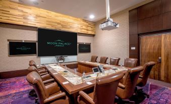 a conference room with a large wooden table surrounded by chairs and a projector screen displaying the moon palace logo at Moon Palace Jamaica
