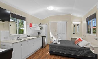 a clean and well - organized bedroom with a bed , kitchen cabinets , and a sink in the background at Discovery Parks – Biloela