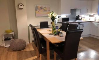 a modern dining room with a wooden table and black chairs , surrounded by white walls and wooden floors at Atlantic Lodge