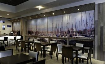 a restaurant with wooden tables and chairs , and a large mural of boats on the wall at Costa Bahia Hotel, Convention Center and Casino