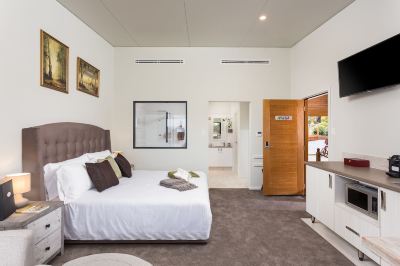 a large bedroom with a king - sized bed , a bathroom , and a doorway leading to a bathroom at The Swan Valley Retreat