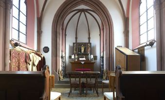 a grand church interior with arched arches , wooden pews , and a desk with books and instruments at Burg Reichenstein
