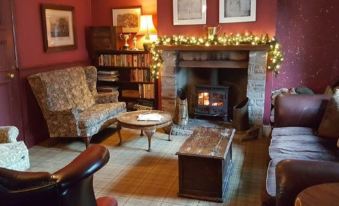 a cozy living room with a fireplace , furniture , and decorations , creating a warm and inviting atmosphere at The Oakhill Inn