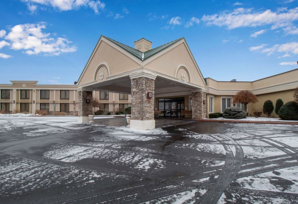 a large building with a covered entrance and a car parked in front of it at Buffalo Airport Hotel