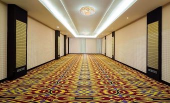a long , empty hallway with colorful carpet and white walls , leading to a brightly lit room at the end at Best Western Plus Makassar Beach