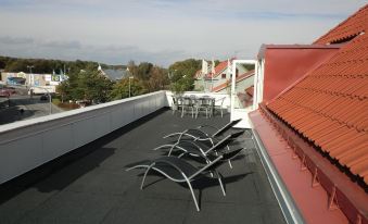 a rooftop with several lounge chairs and a table , providing a comfortable outdoor space for relaxation at Port Hotel