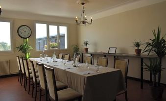 a long dining table set for a formal dinner , with several chairs arranged around it at Le Cheval Blanc - Logis Hotel