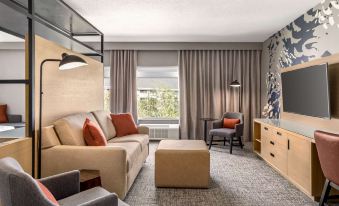 a modern living room with a beige couch , wooden coffee table , and gray carpeting , surrounded by two chairs and a window at Doubletree by Hilton Columbus Dublin