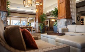 a hotel lobby with a couch , chairs , and tables , as well as potted plants and hanging lights at Hilton Garden Inn Boise/Eagle