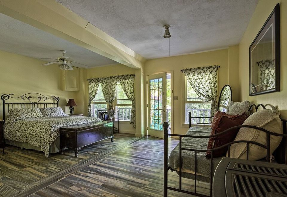 a bedroom with a large bed , couch , and rocking chair is shown with wooden flooring at Sylvan Falls Mill B&B