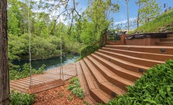 a wooden staircase leads up to a swing set in a lush green area with trees at Stone Waters Inn